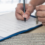 man signing a rent to own agreement with sun filled window in background