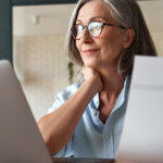 mature woman studying tax write-offs and smiling at the discovery of another benefit