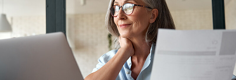 a mature woman studying tax write-offs and smiling at the discovery of another benefit