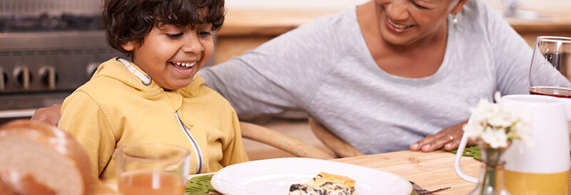 smiling child and senior enjoying each other at breakfast table after grandma downsized here house