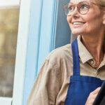a smiling woman in work apron working down checklist saving money on rental repairs
