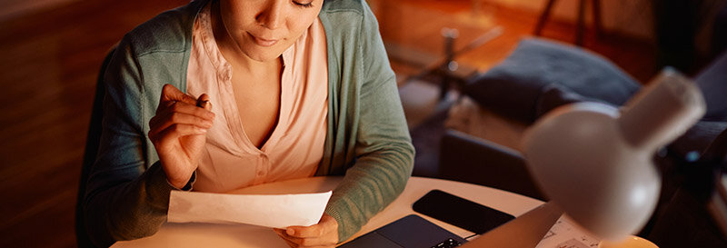 woman reads mortgage loan documents at kitchen table during pre-foreclosure