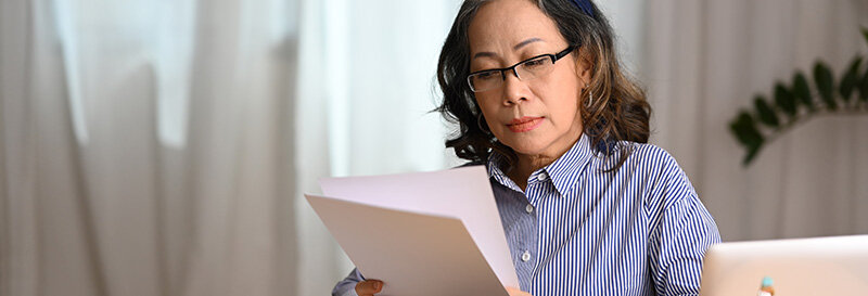 woman reviews records of her rental property at home with warm light and window in background at table with laptop