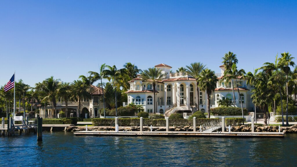 Luxury waterfront mansion surrounded by palm trees