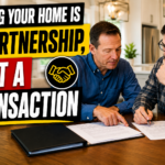 Homeowner and home buyer reviewing real estate documents together at a table.