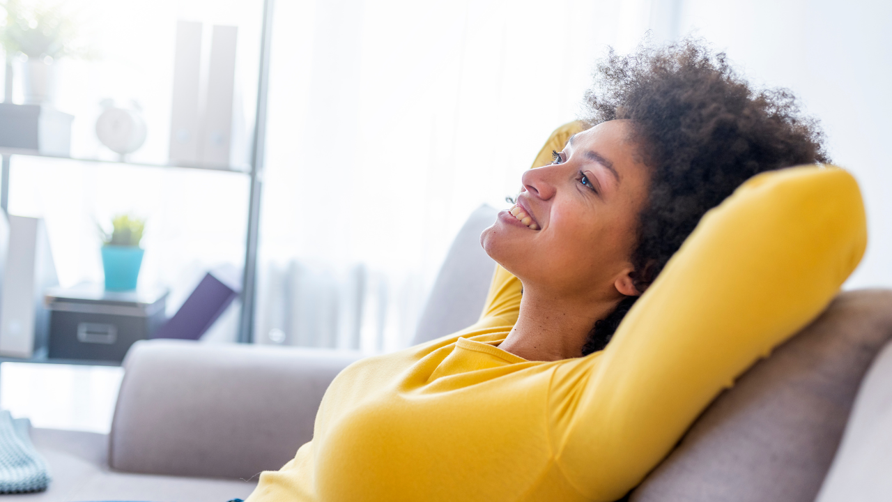 Happy woman relaxing on comfortable soft sofa enjoying stress free weekend at home