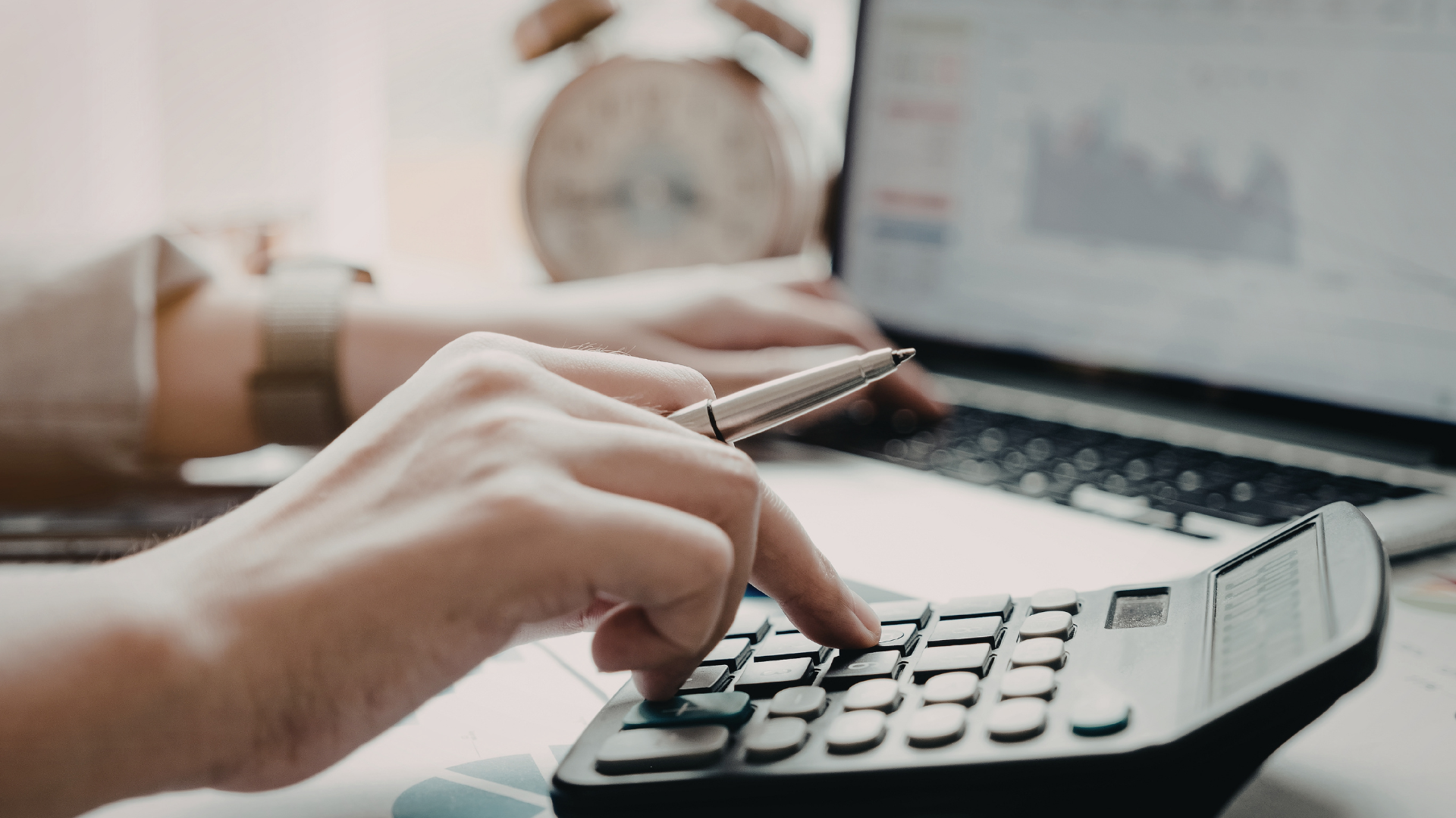 Investor reviewing numbers on laptop + calculator