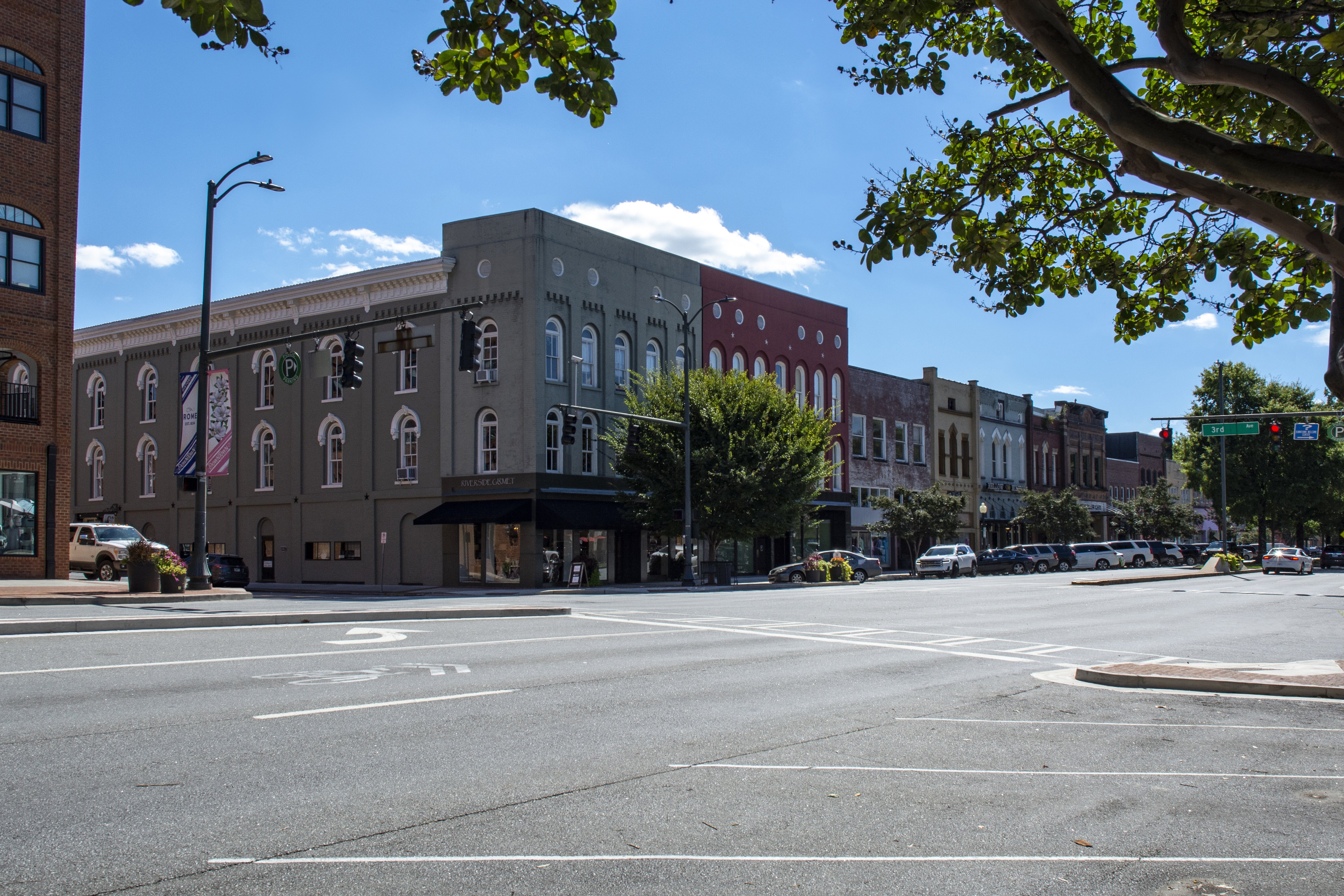 A street in downtown Rome, Georgia, lined with historic brick buildings, local shops, and parked cars.