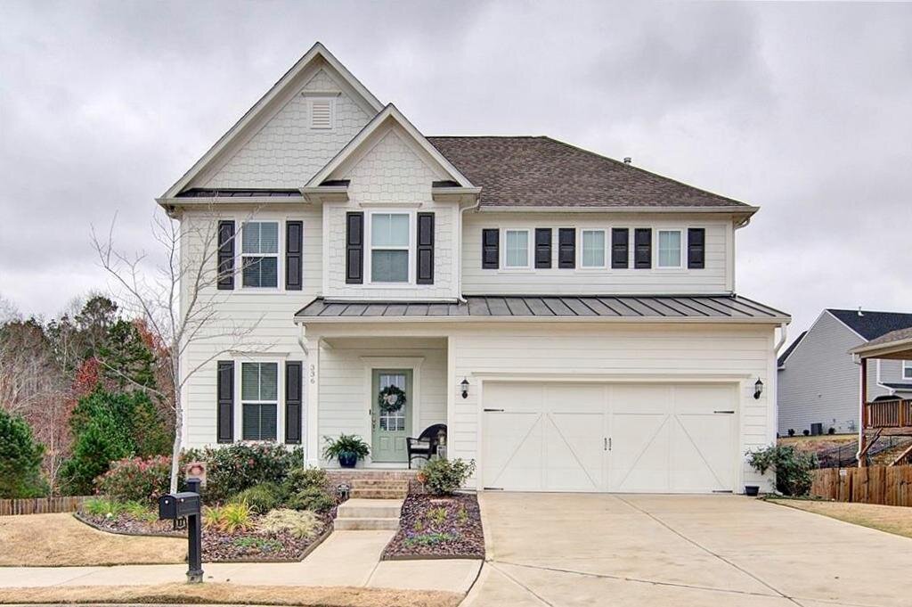White two-story house in Canton, GA with black shutters and green door.
