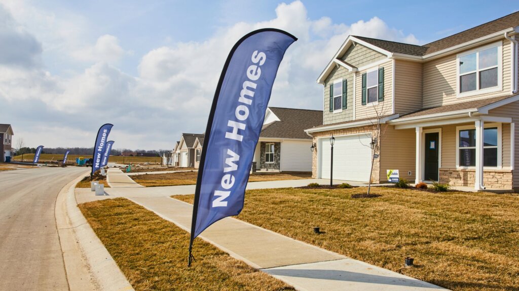 Exterior of a newly built home in a new construction community with a 'New Homes' sign out front.