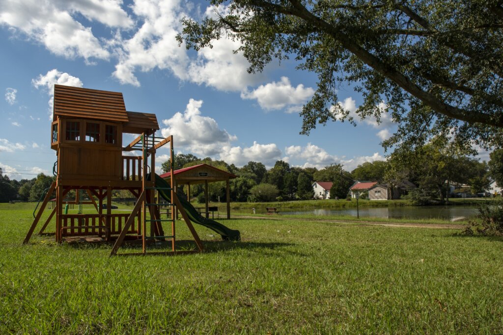 Scenic view of a lake in Floyd County, GA, with a family’s playset in the foreground and homes along the waterfront.