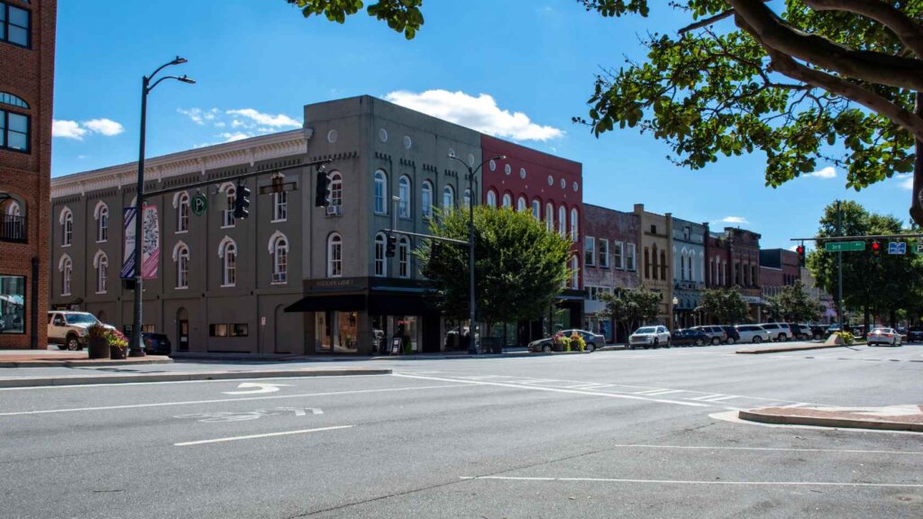 A street in downtown Rome, Georgia, lined with historic brick buildings, local shops, and parked cars.