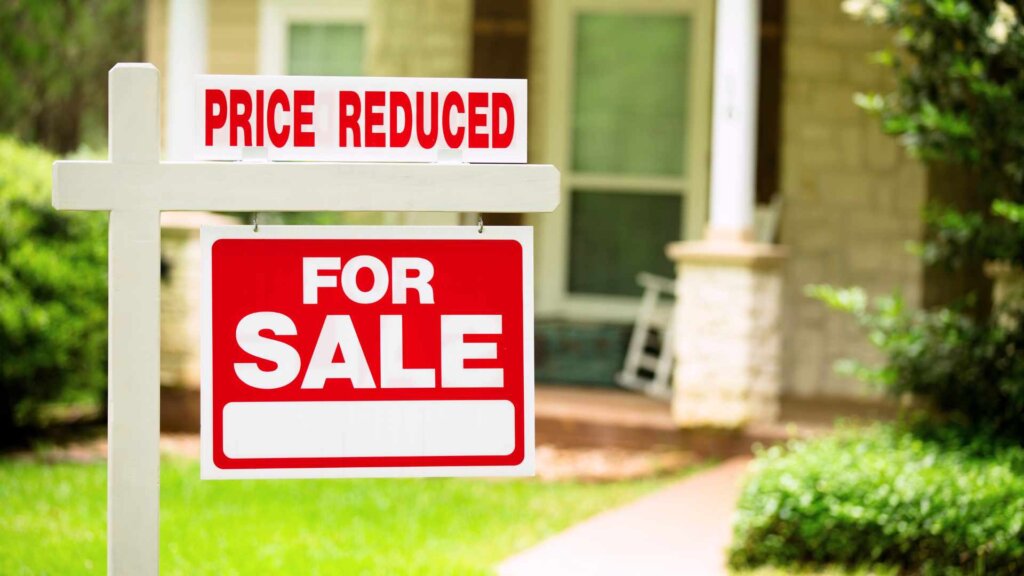 Home for sale with price reduction sign in front yard