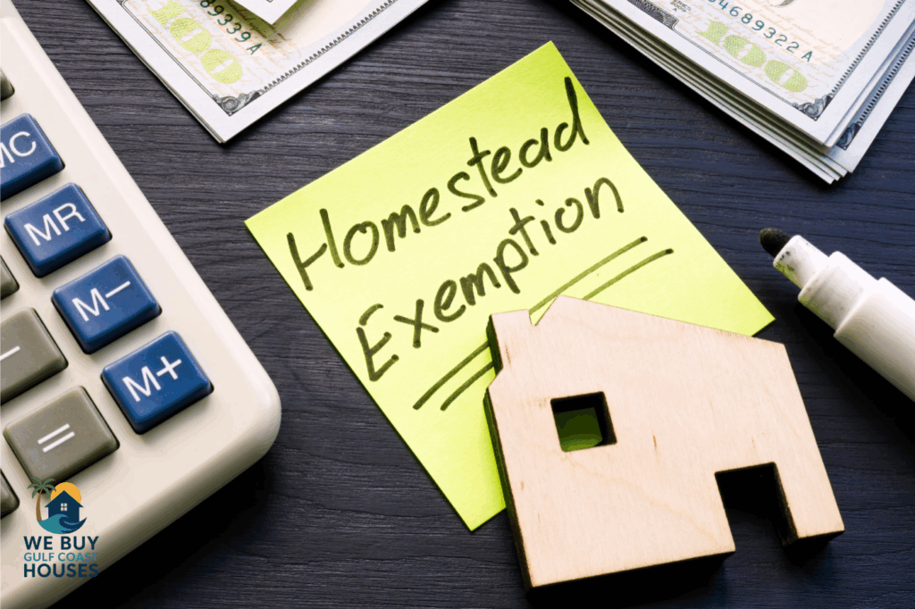 Calculator, cash, wooden house, and sticky note reading ‘Homestead Exemption’ for Florida property tax savings.