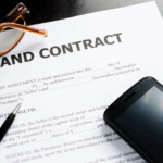 Florida land contract agreement with phone, pen, and reading glasses on a desk.