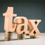 Wooden tax letters on stacks of coins with We Buy Gulf Coast Houses logo