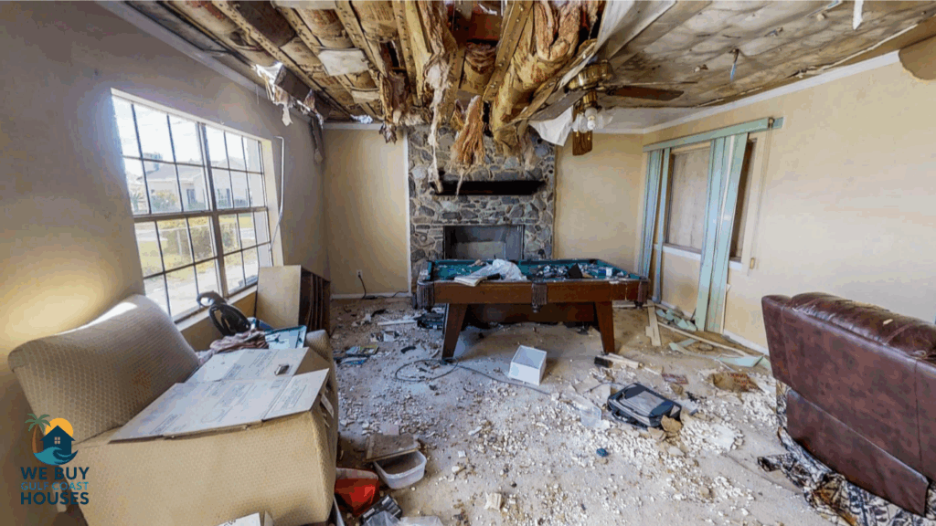 Destroyed rental home interior with ceiling damage, debris, and broken furniture — typical of severe tenant-caused property damage.