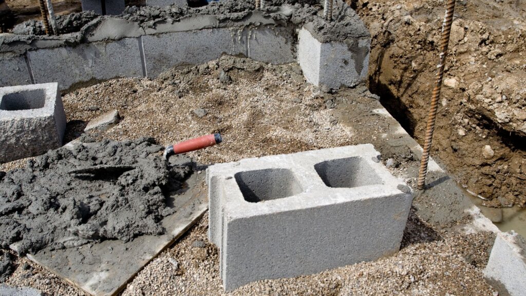 Cinder block foundation under construction, with stacked concrete blocks forming the base walls of a building.