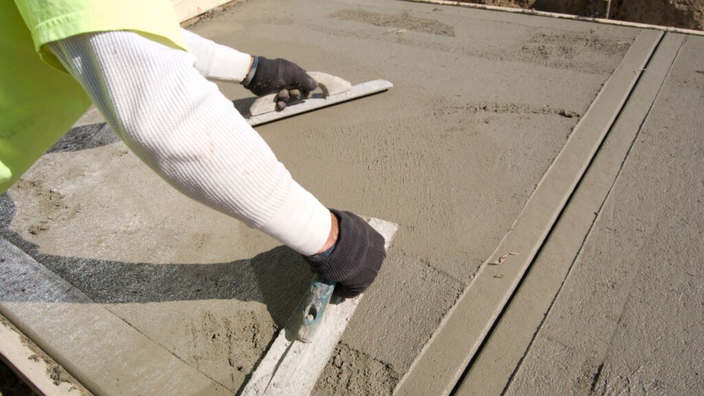 Contractor spreading wet cement for a sidewalk.