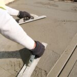 Contractor spreading wet cement for a sidewalk.