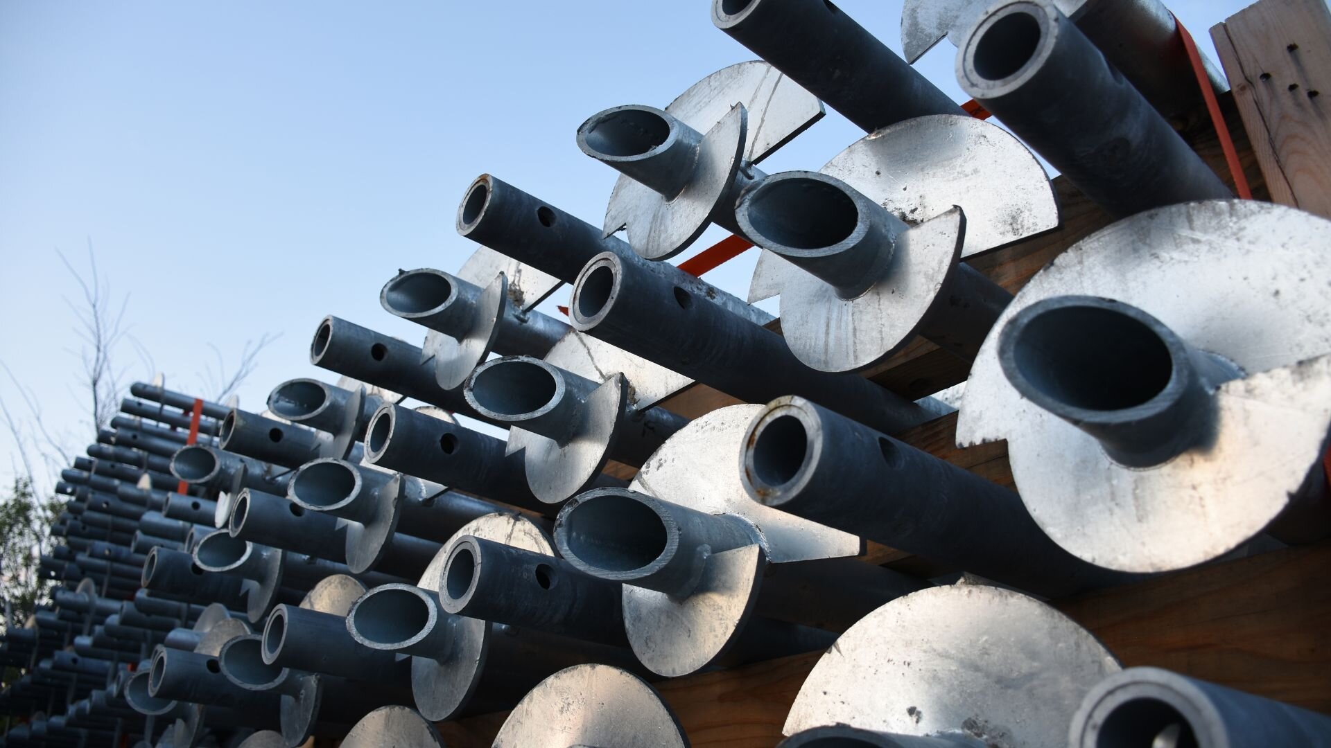 Close-up view of stacked helical piers with spiral plates, used for deep foundation support in construction.