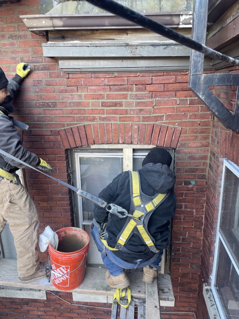 Contractors working on exterior of brick building in Boston, MA.