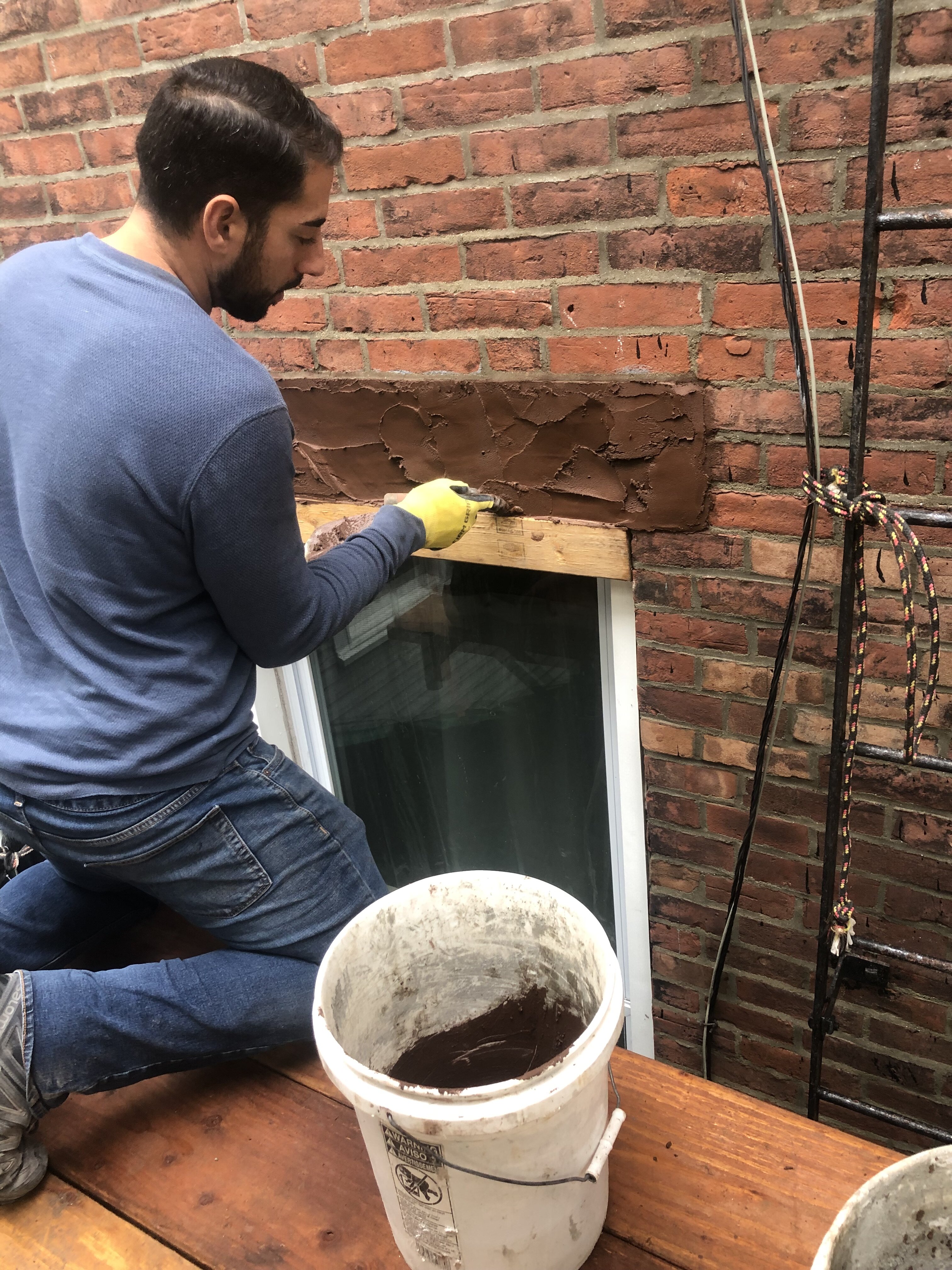 Contractor applying waterproofing material to brick wall in Boston, MA.
