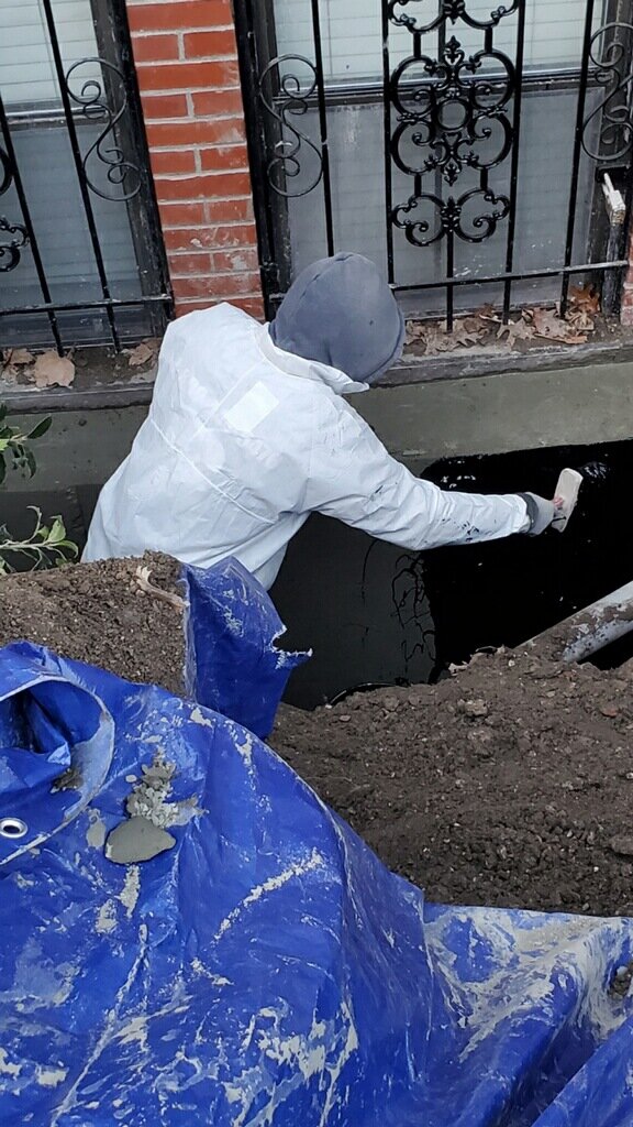 Contractor applying waterproofing material to a basement in Boston, MA.