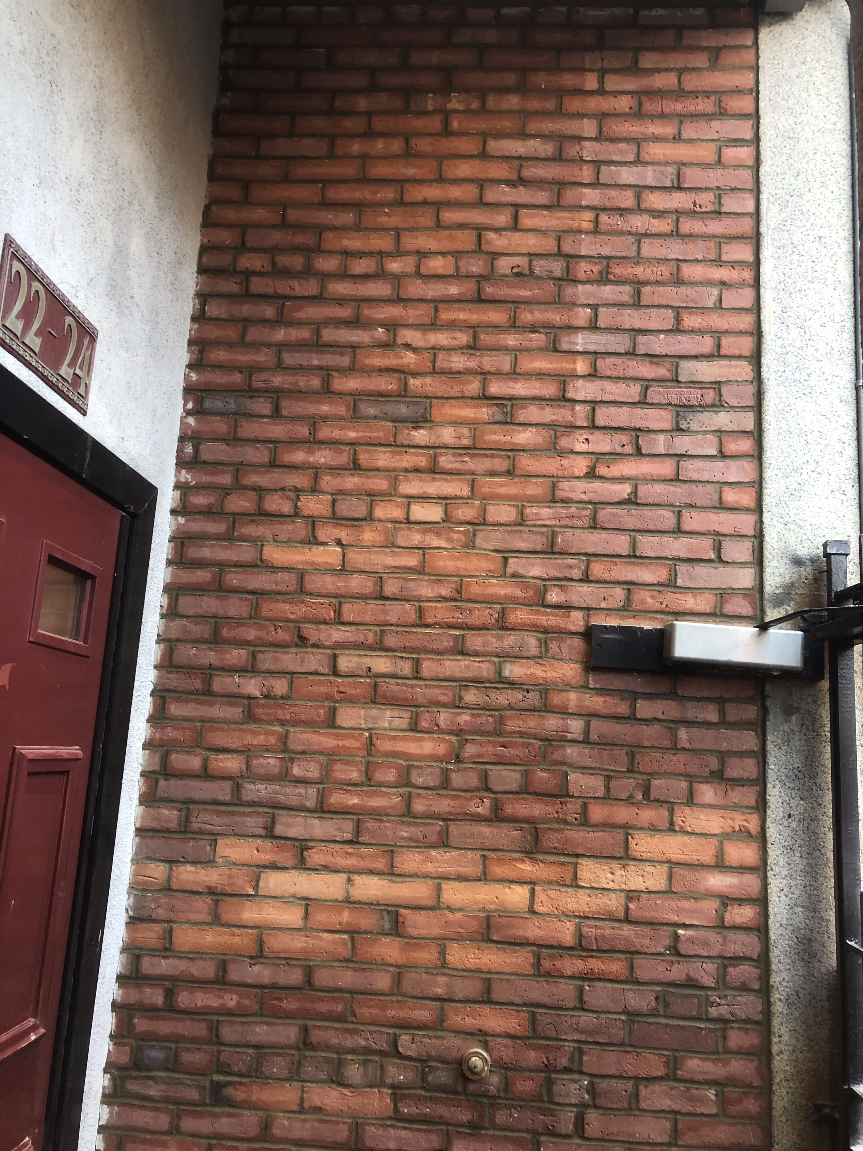 Newly waterproofed brick wall outside of an apartment door in Boston, MA.