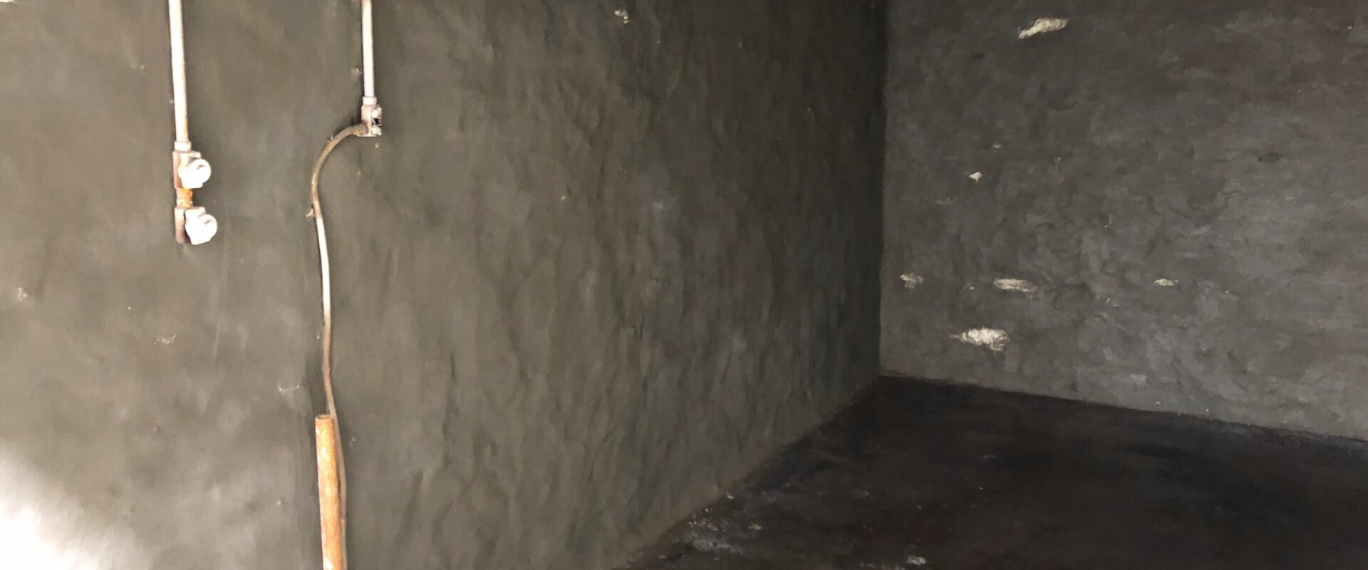Basement interior with waterproofing material applied to the walls to prevent moisture intrusion.