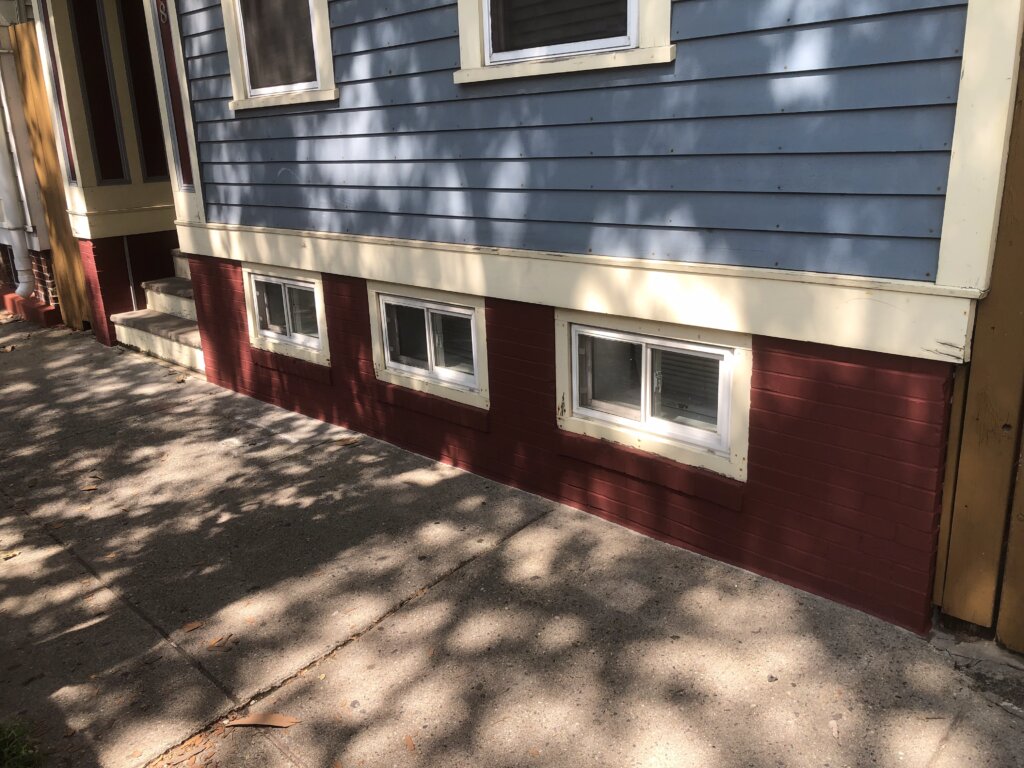 Row of connected houses in Boston, with one featuring small basement windows near the ground level.
