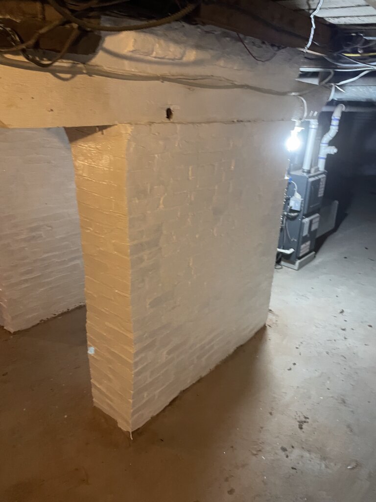 Basement foundation arch featuring newly laid brick and fresh white paint, highlighting recent restoration work.