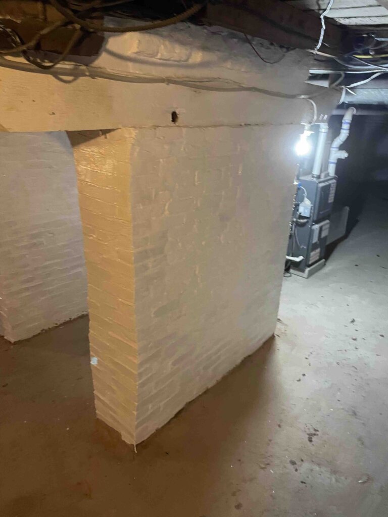 Basement foundation arch featuring newly laid brick and fresh white paint, highlighting recent restoration work.