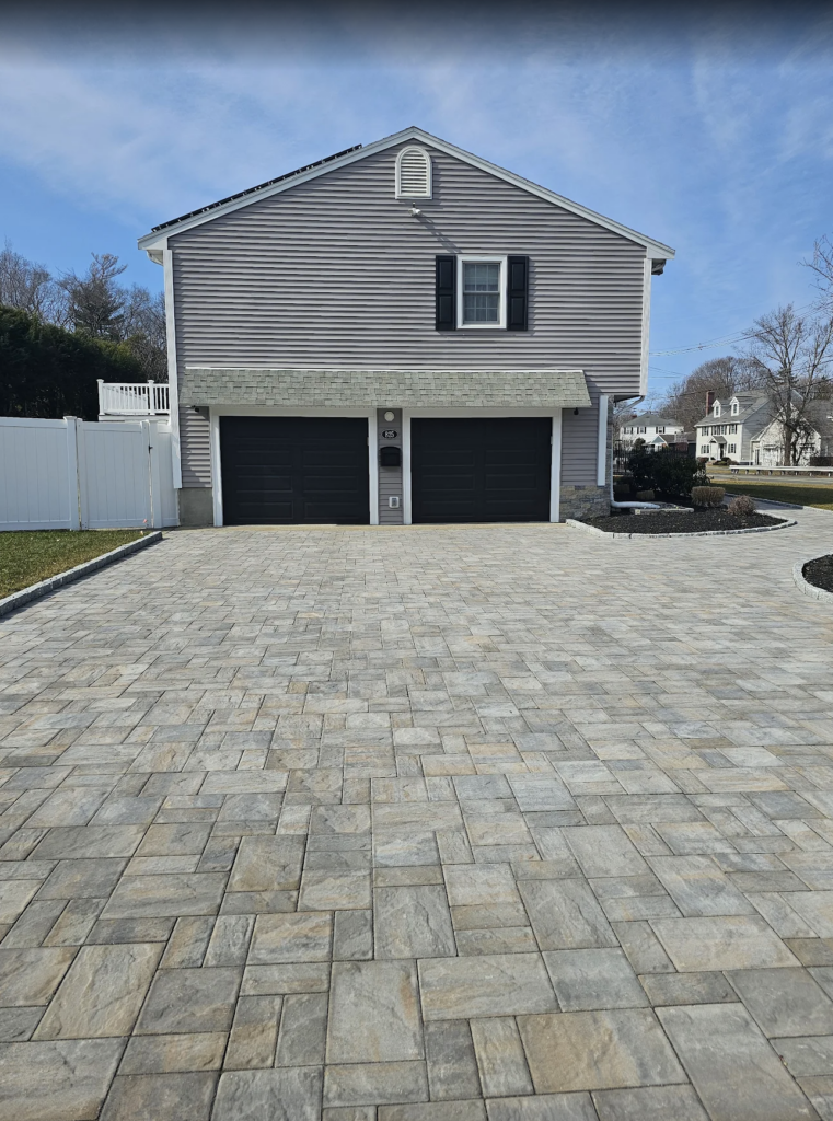 Side view of a Boston, MA house highlighting the stone exterior and a wide stone driveway leading to the garage.