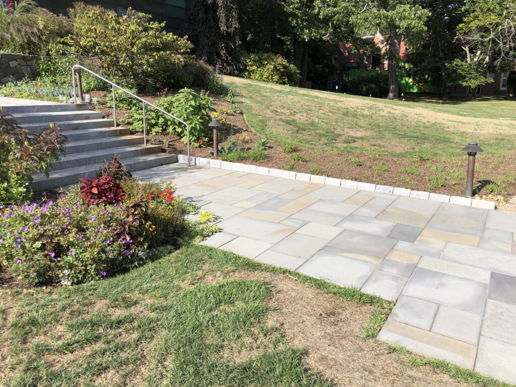 A stone walkway leading to the entrance of a commercial building, surrounded by well-maintained landscaping.