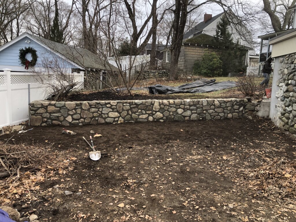 Newly constructed stone retaining wall with clean, even layers of stacked stones in Boston, MA.
