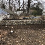 Newly constructed stone retaining wall with clean, even layers of stacked stones in Boston, MA.