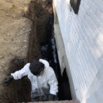 Contractor applying waterproofing material to a basement in Boston, MA.