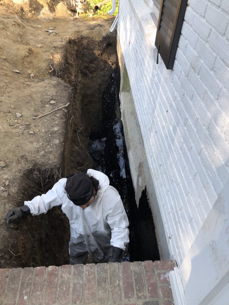 Contractor applying waterproofing material to a basement in Boston, MA.