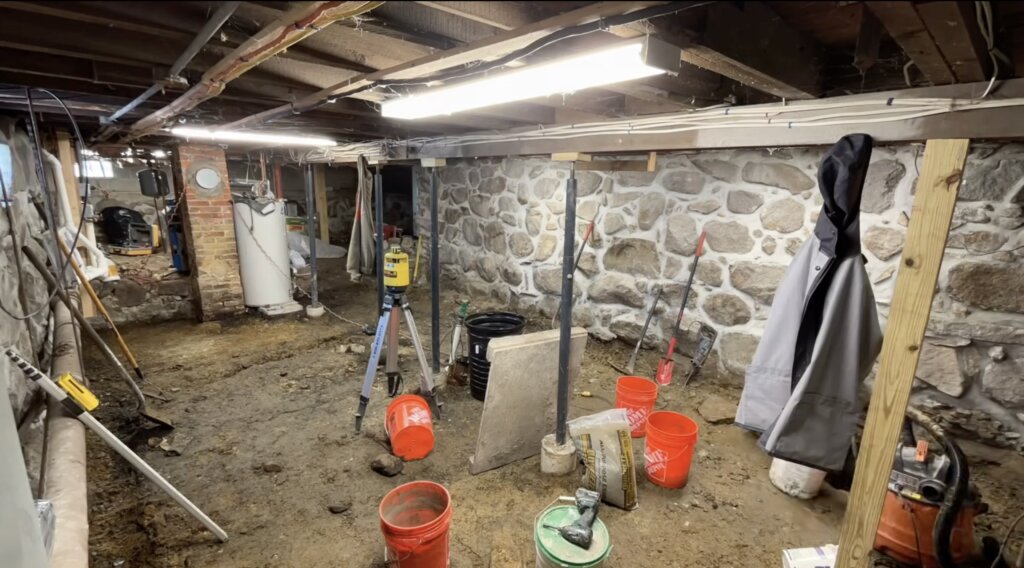 Basement foundation repair project in progress with restored stone walls and structural supports