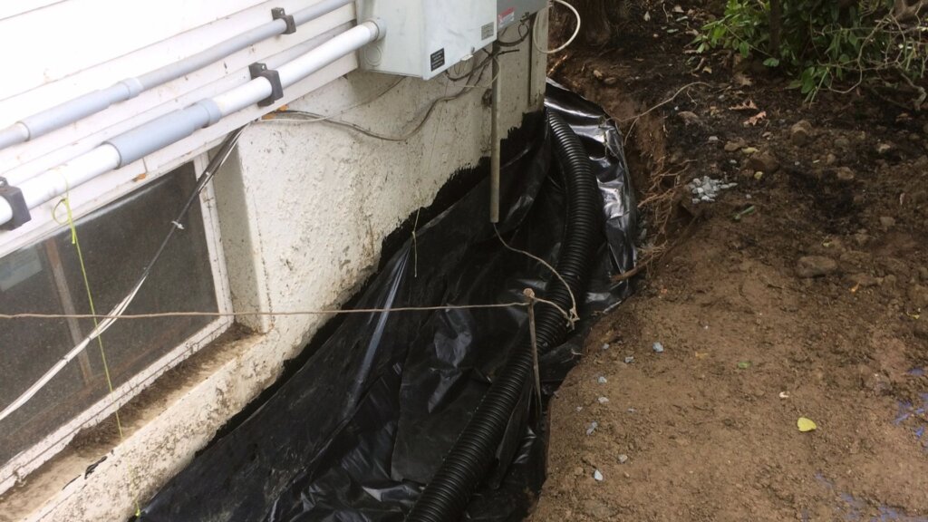 Basement waterproofing installation featuring foundation drainage and exterior moisture protection