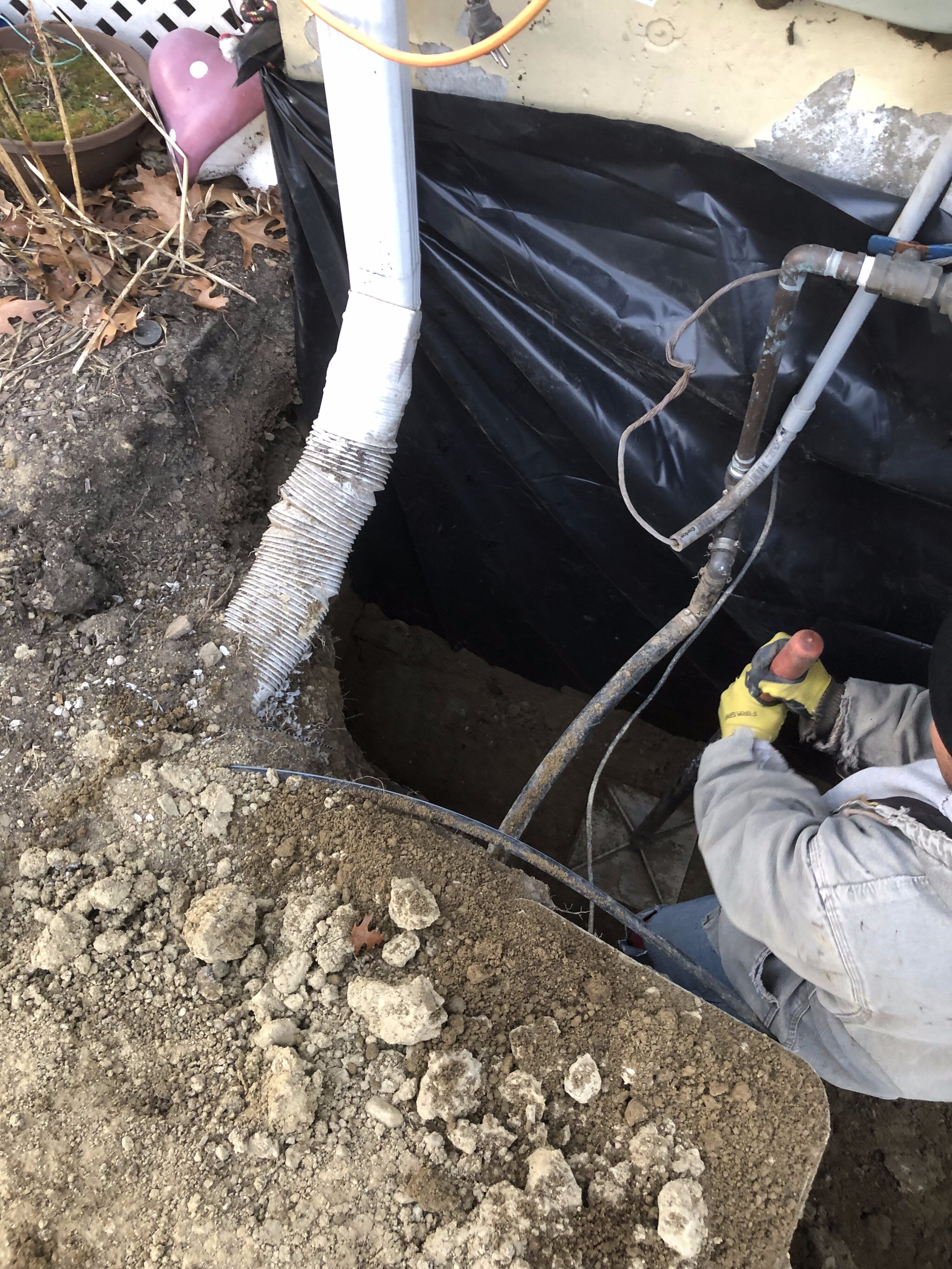 Contractor installing an exterior waterproofing membrane to protect a home's foundation from moisture intrusion