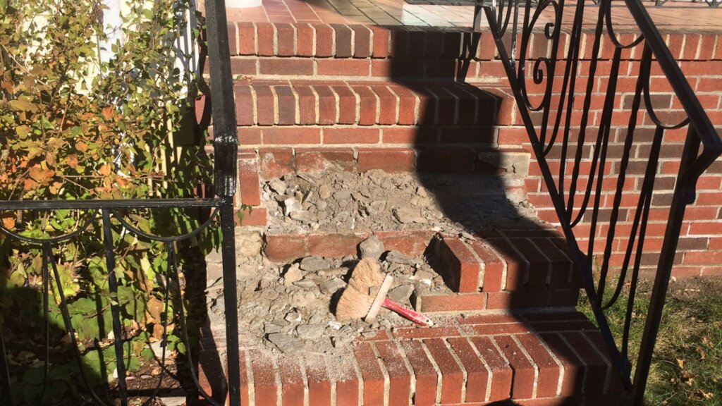 Damaged brick steps undergoing masonry repair and restoration at a residential property in Boston, MA