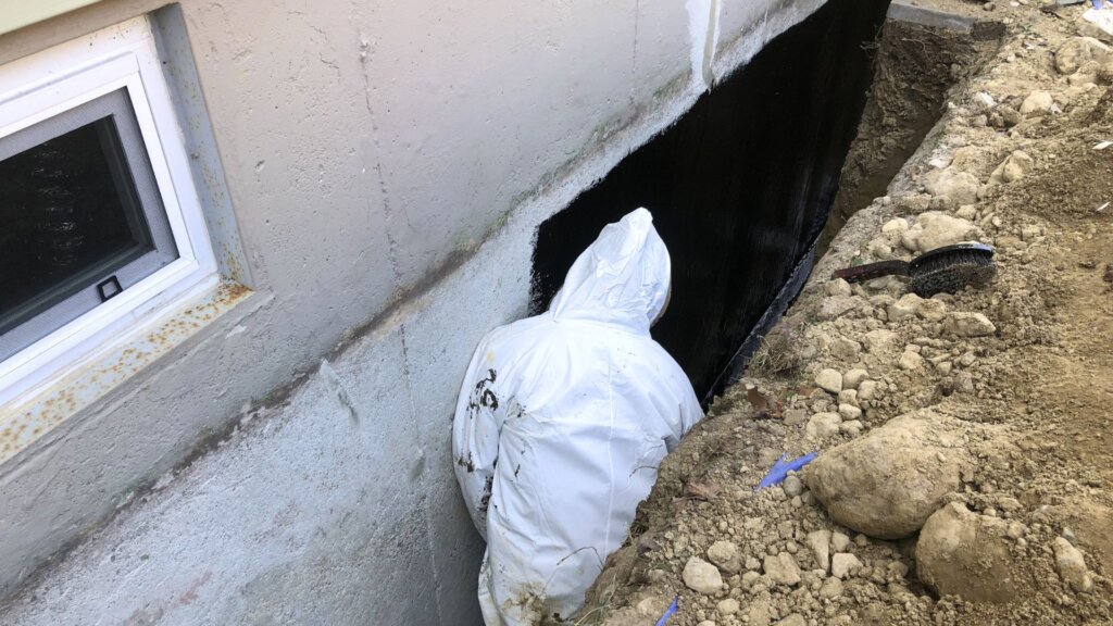 Exterior waterproofing project involving excavation and application of a waterproof coating to a home's foundation wall