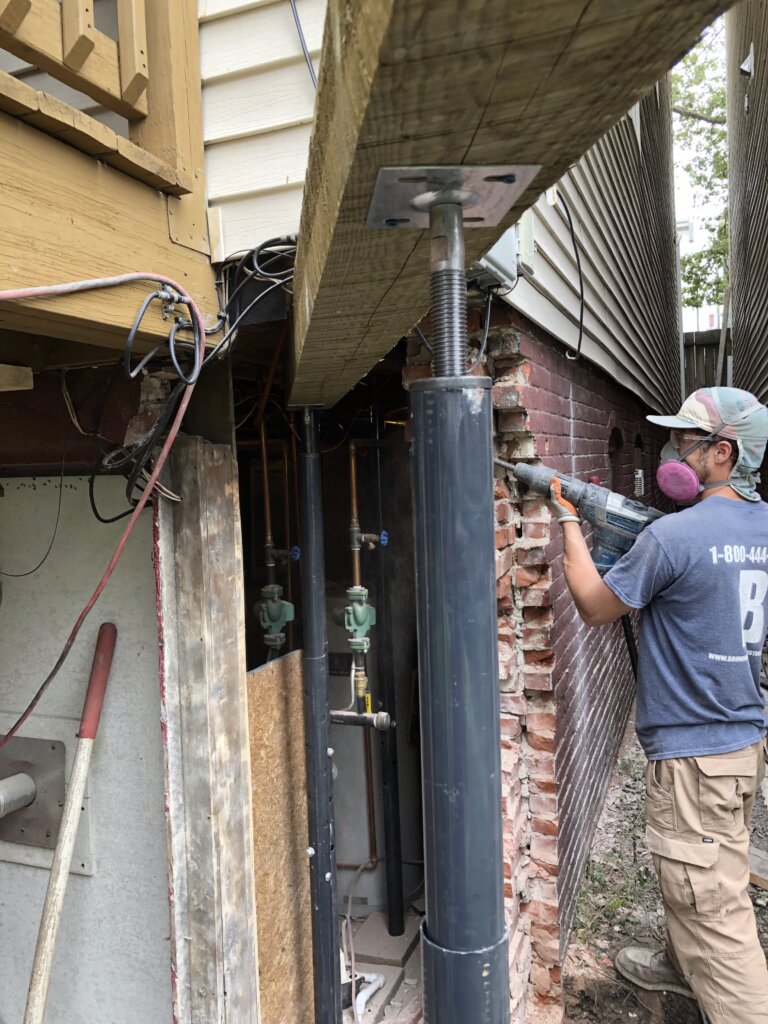 Foundation repair technician removing damaged brick masonry during a structural repair project