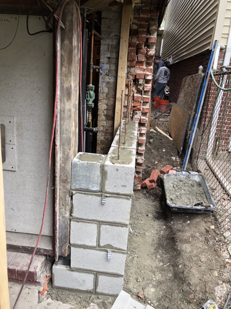 New concrete block foundation wall being constructed during a structural repair project