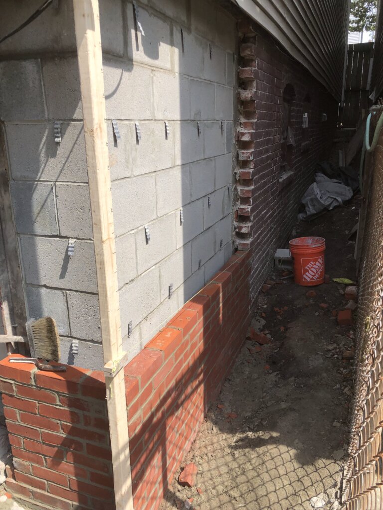 Foundation wall reconstruction with new concrete block and brick masonry installation