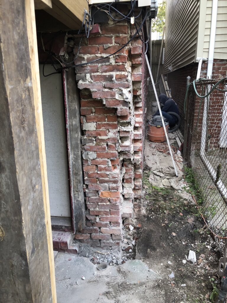 Severely deteriorated brick foundation wall undergoing repair and stabilization