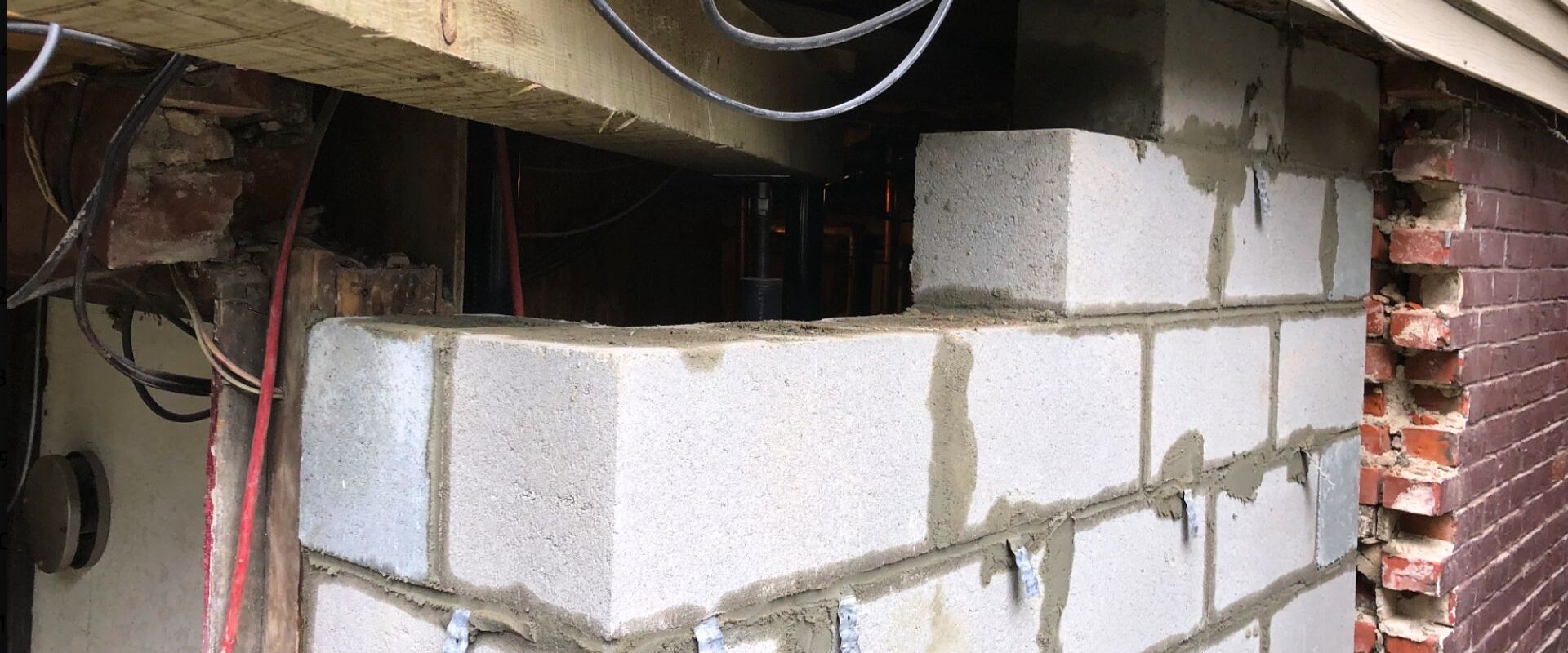 Foundation repair work involving structural support installation and masonry rebuilding