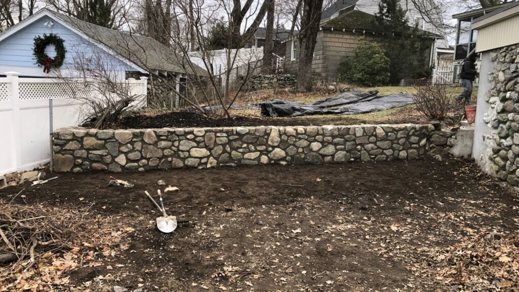 Restored historic fieldstone retaining wall on a residential property in Boston, MA